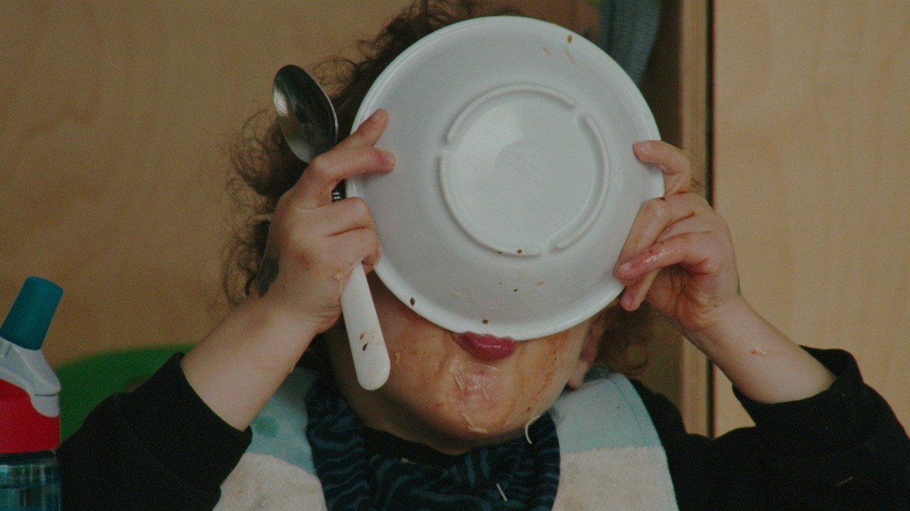 A toddler drinking from a bowl covering their face